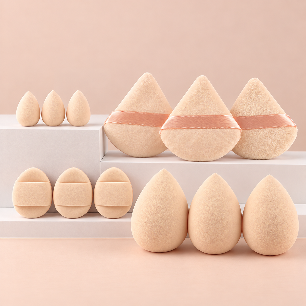 Beige makeupsvampar och puffar uppställda på podier mot persikofärgad bakgrund